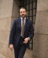 Navy flannel suit with striped shirt, olive wool tie and white pocket square, worn by a model on a city street