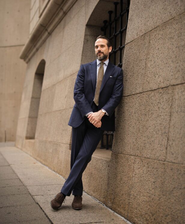 Navy flannel suit with striped shirt, brown tie and brown suede derbies, worn by a model on a city street