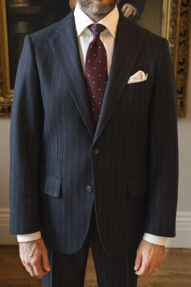 Navy chalk stripe flannel suit with white shirt, burgundy dotted tie and white pocket square, worn by a model