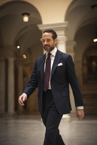 Navy chalk stripe flannel suit with white shirt, burgundy dotted tie and white pocket square, worn by a model