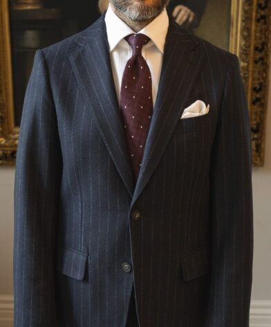 Navy chalk stripe flannel suit jacket with white shirt, burgundy dotted tie and cream pocket square, worn by a model