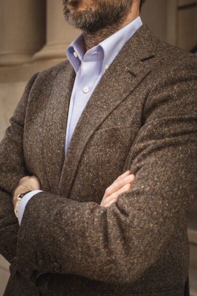 Brown donegal tweed sport coat with light blue button-down shirt, close-up on the lapel and sleeve, worn by a model