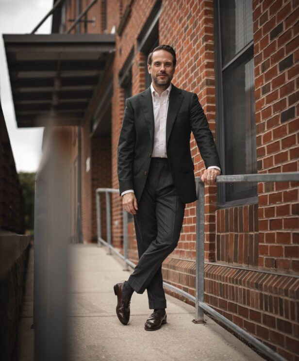 Forest green flannel sport coat with white shirt, charcoal trousers and brown loafers, worn by a model on a brick sidewalk