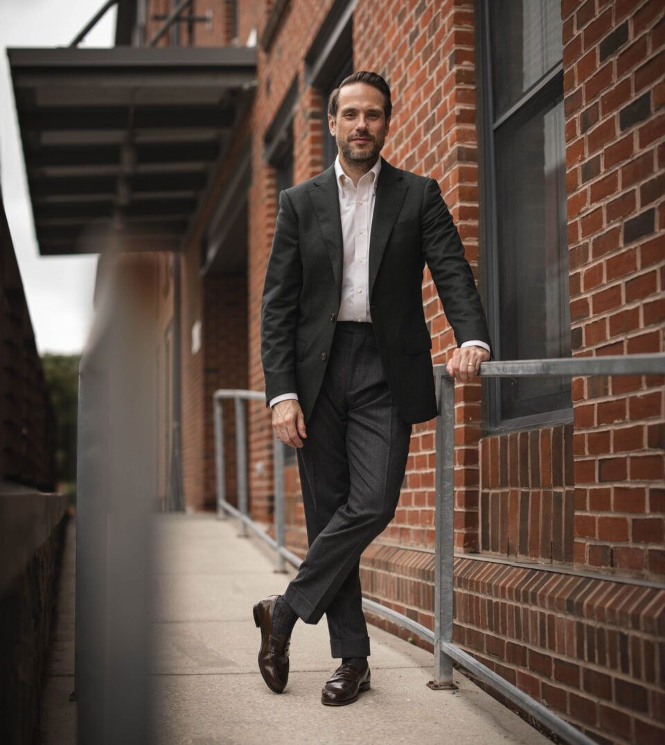 Forest green flannel sport coat with white shirt, charcoal trousers and brown loafers, worn by a model on a brick sidewalk