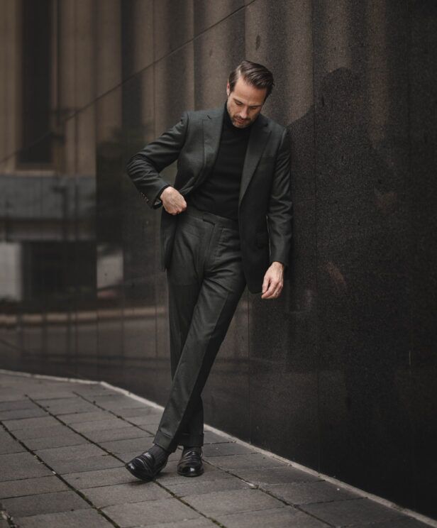 Dark forest green flannel suit with black turtleneck and black loafers, worn by a model on a city street