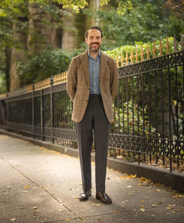 Brown glen plaid flannel sport coat with denim shirt, charcoal trousers and brown loafers, worn by a model on a city sidewalk