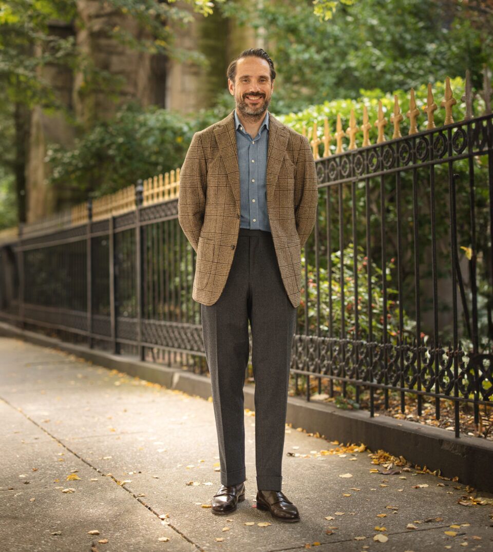 Brown glen plaid flannel sport coat with denim shirt, charcoal trousers and brown loafers, worn by a model on a city sidewalk