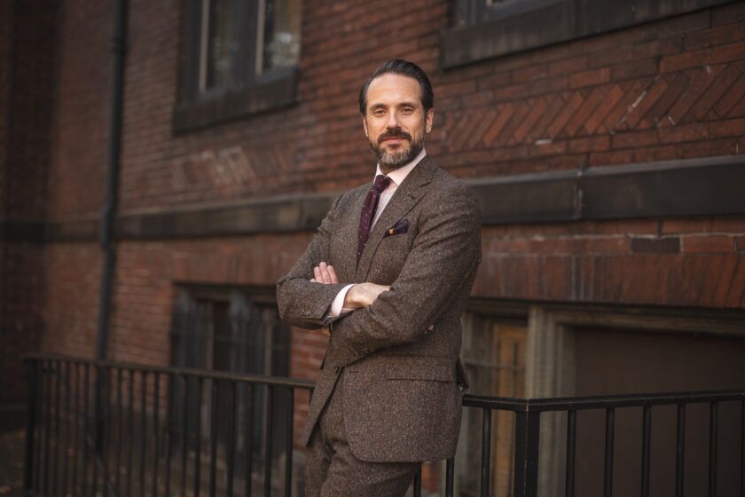 Brown donegal tweed suit with pink shirt and burgundy dotted tie, worn by a model on a city street