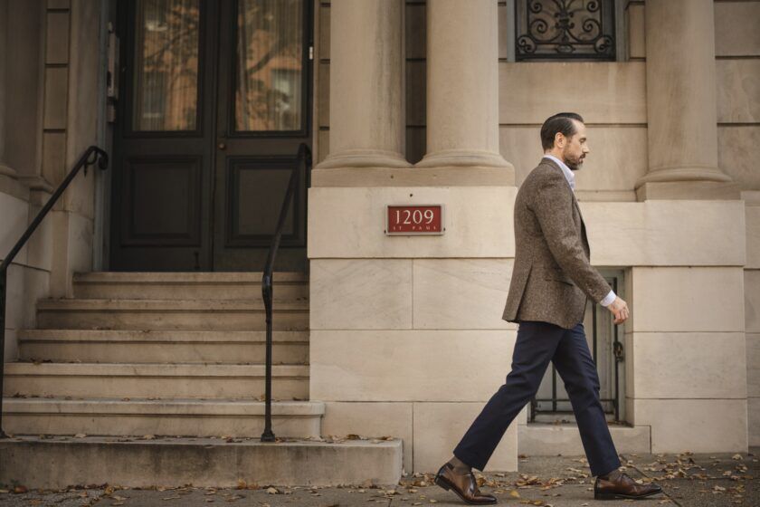 Brown donegal tweed sport coat with white shirt, navy trousers and brown oxfords, worn by a model on a city street