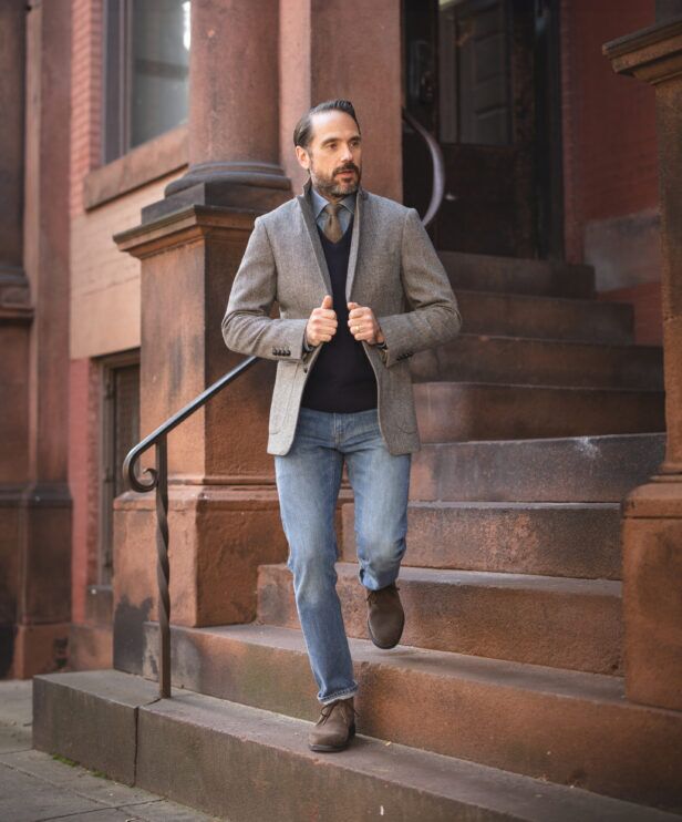 Grey herringbone tweed sport coat with navy sweater, chambray shirt and jeans, on brownstone steps
