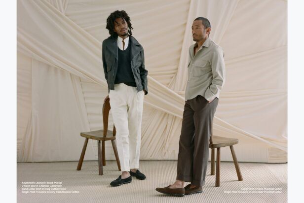 Black leather asymmetric jacket with charcoal vest beside a sand camp shirt, worn by two models