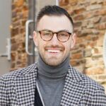 Black and white checked wool sport coat with grey turtleneck, worn by a smiling model outdoors