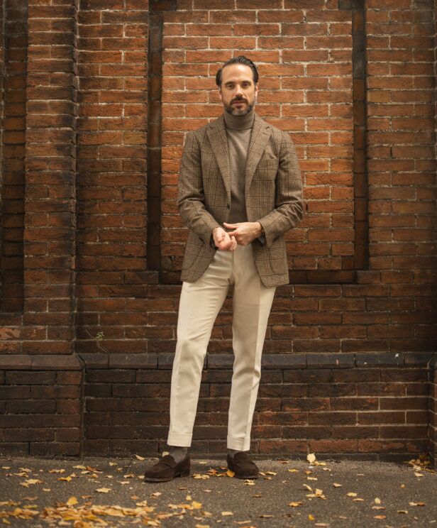 Brown glen plaid wool sport coat with taupe turtleneck, cream trousers and brown suede loafers, worn by a model