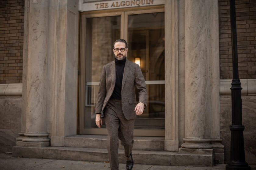 Brown donegal tweed suit with black turtleneck and black loafers, worn by a model on a city street