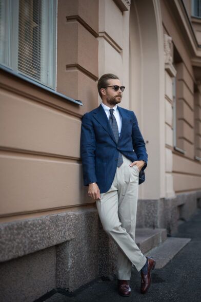 Navy linen sport coat with medallion silk tie, cream trousers and burgundy tassel loafers, on a street