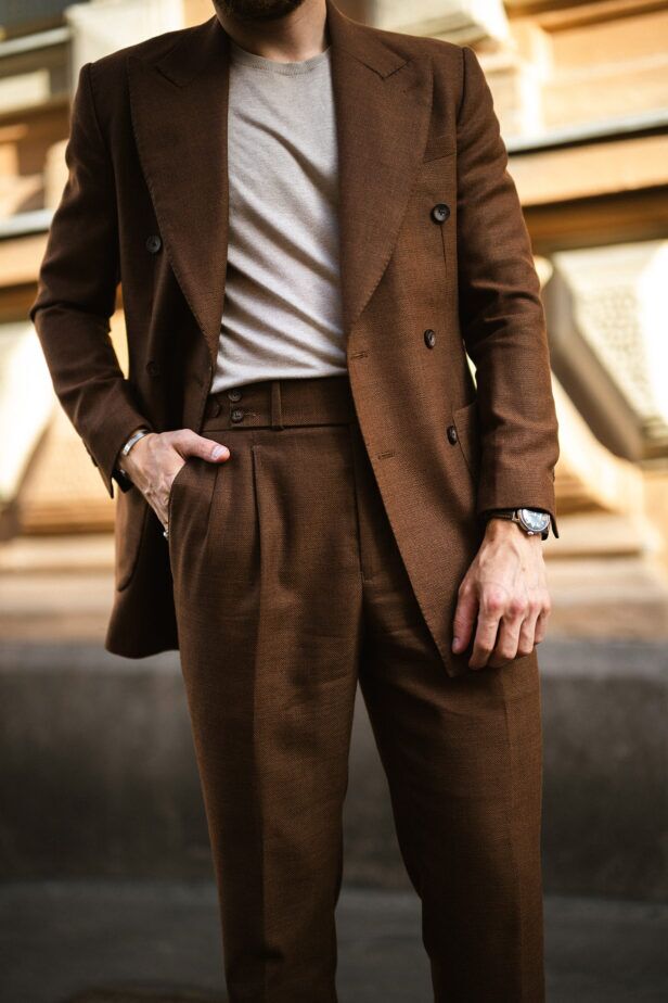 Brown double-breasted hopsack suit with peak lapels and pleated trousers over a cream tee, worn by a model