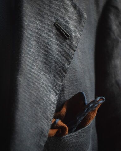 Rust and navy wool pocket square in the breast pocket of a grey flannel sport coat, close-up detail