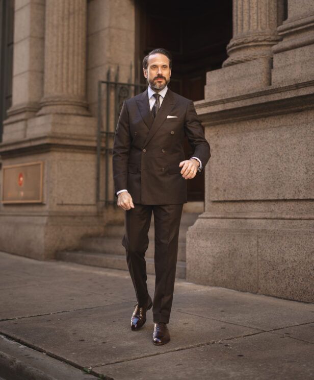 Brown double-breasted wool suit with white shirt, patterned tie and brown oxfords, worn by a model on a city street