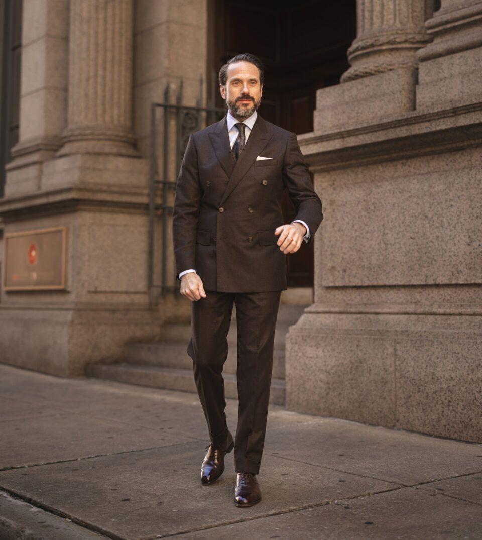 Brown double-breasted wool suit with white shirt, patterned tie and brown oxfords, worn by a model on a city street