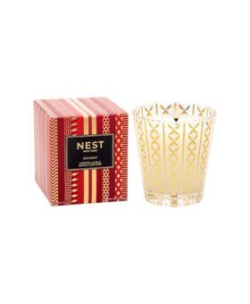 Holiday scented candle in gold-patterned glass tumbler beside its red and gold gift box, packaging shot