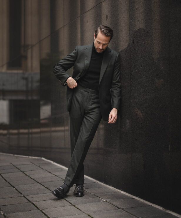 Dark green flannel suit with black turtleneck and black loafers, worn by a model on a city street