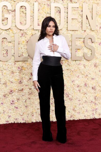 White pleated-bib tuxedo shirt with black satin cummerbund and black velvet flared trousers, worn on a red carpet