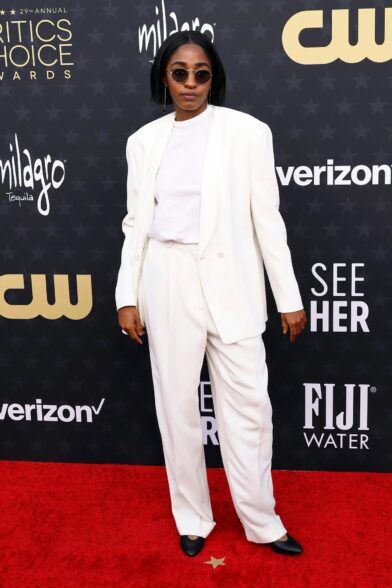 Cream collarless suit with wide-leg trousers, white tee and black flats on a red carpet, styled scene