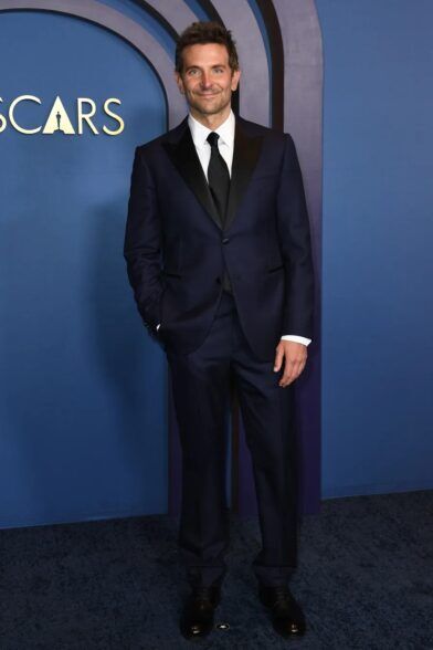 Midnight blue tuxedo with black peak lapels, white shirt and black tie, worn on a red carpet