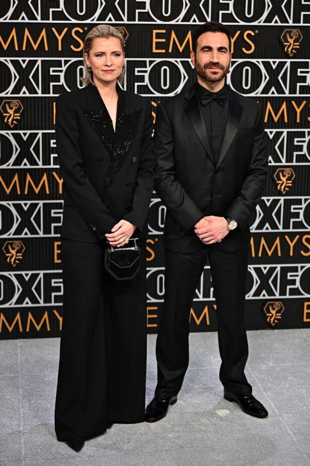 Black peak lapel tuxedo with satin facings, pleated black shirt and black bow tie, worn on a red carpet