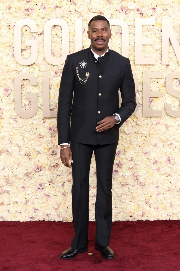 Black mandarin-collar dinner suit with pearl buttons and jeweled brooches, worn on a red carpet