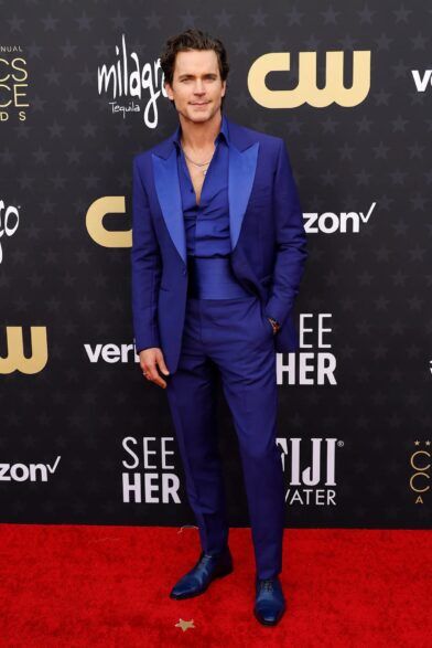 Royal blue tuxedo with satin peak lapels, matching shirt, cummerbund and blue shoes, worn on a red carpet