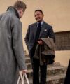 Charcoal flannel suit with blue shirt and navy tie, worn among men in grey and navy overcoats