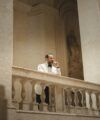 Off-white shawl collar dinner jacket with black bow tie and black trousers, worn by a model on a stone balcony