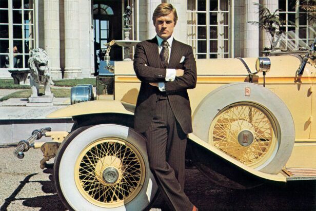 Brown pinstripe suit with blue shirt, patterned tie and white pocket square, worn beside a vintage Rolls-Royce