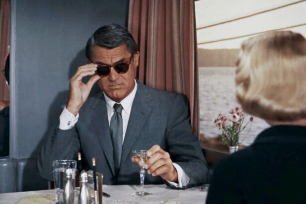 Grey worsted suit with white shirt, grey tie and dark sunglasses, worn in a dining car film scene