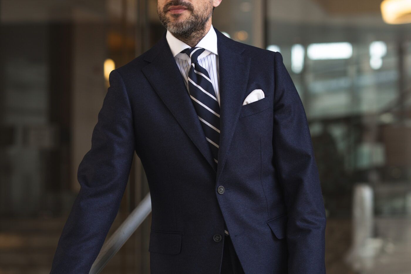 Navy and white striped silk necktie with navy flannel suit, striped shirt and white pocket square, worn by a model
