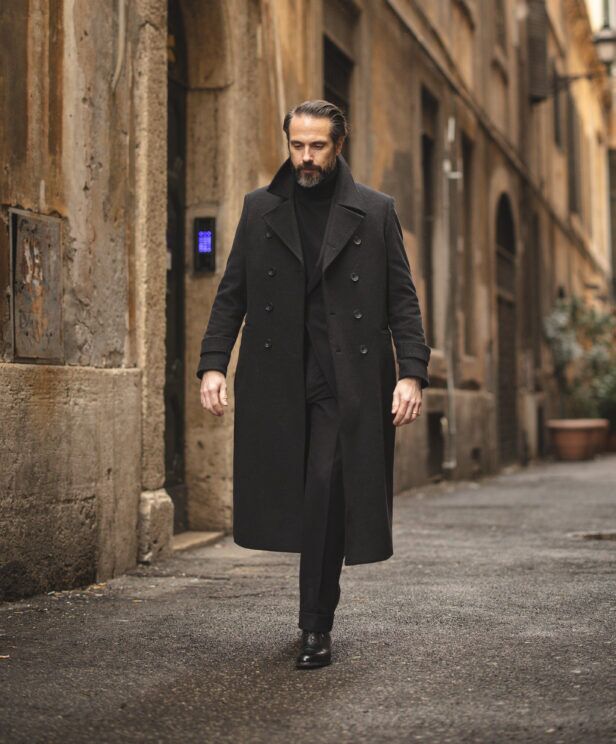 Charcoal double-breasted wool overcoat with black turtleneck, trousers and derbies, worn by a model on a street