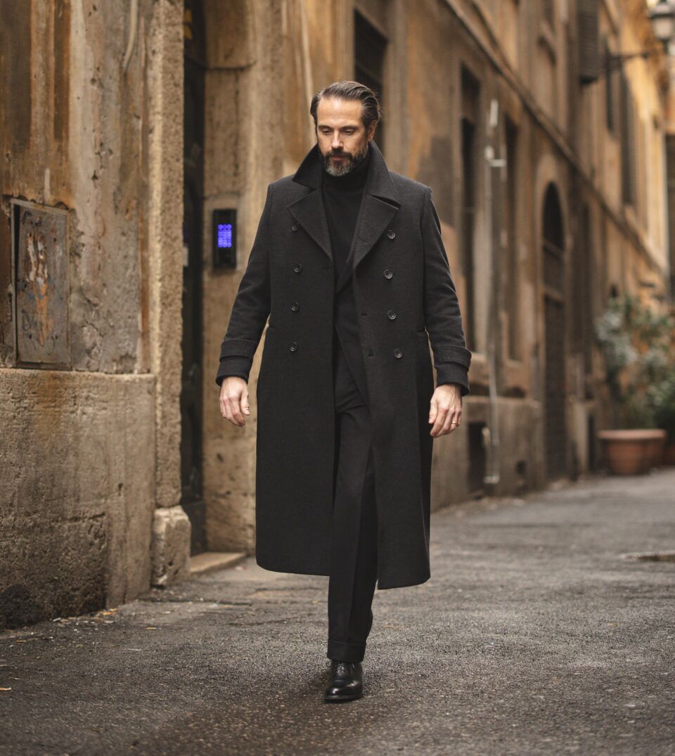 Charcoal double-breasted wool overcoat with black turtleneck, trousers and derbies, worn by a model on a street