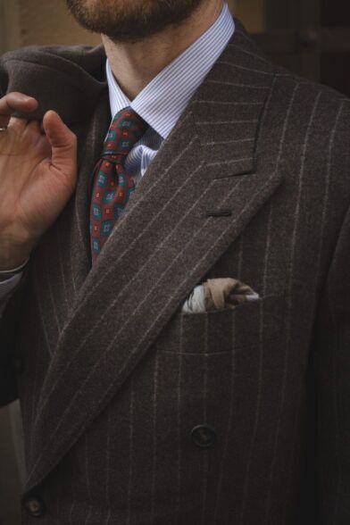 Brown chalk stripe flannel double-breasted suit with blue striped shirt and burgundy medallion tie, a close-up detail