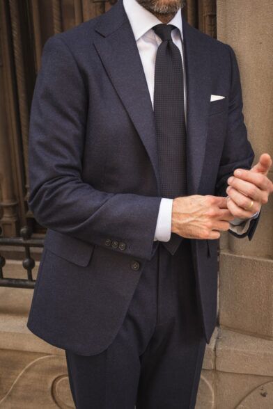 Navy flannel suit with peak lapels, white shirt, navy knit tie and white pocket square, worn by a model