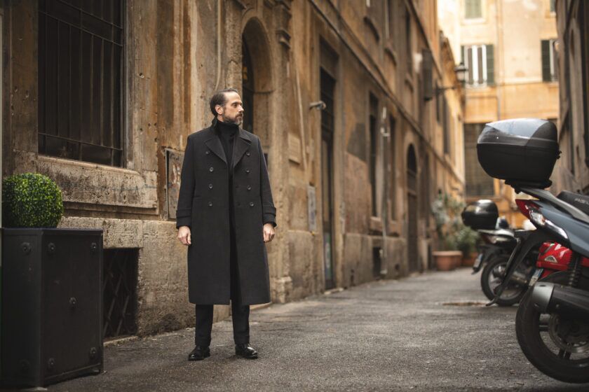Charcoal double-breasted wool overcoat with black turtleneck and trousers, worn by a model on a city street