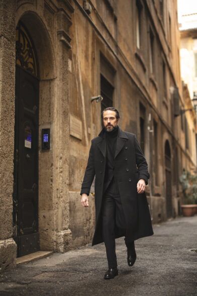 Charcoal double-breasted full-length wool overcoat with black turtleneck, on a cobbled street