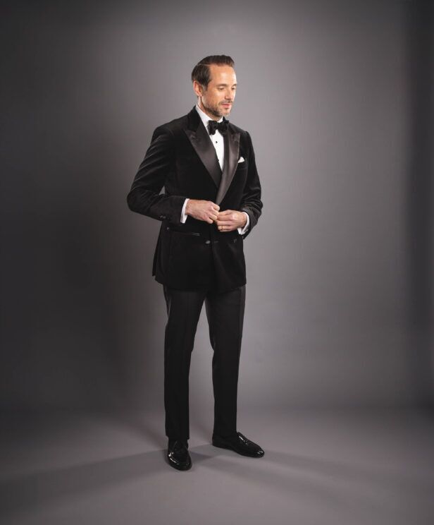 Black velvet double-breasted dinner jacket with satin peak lapels, black bow tie and trousers, worn by a model