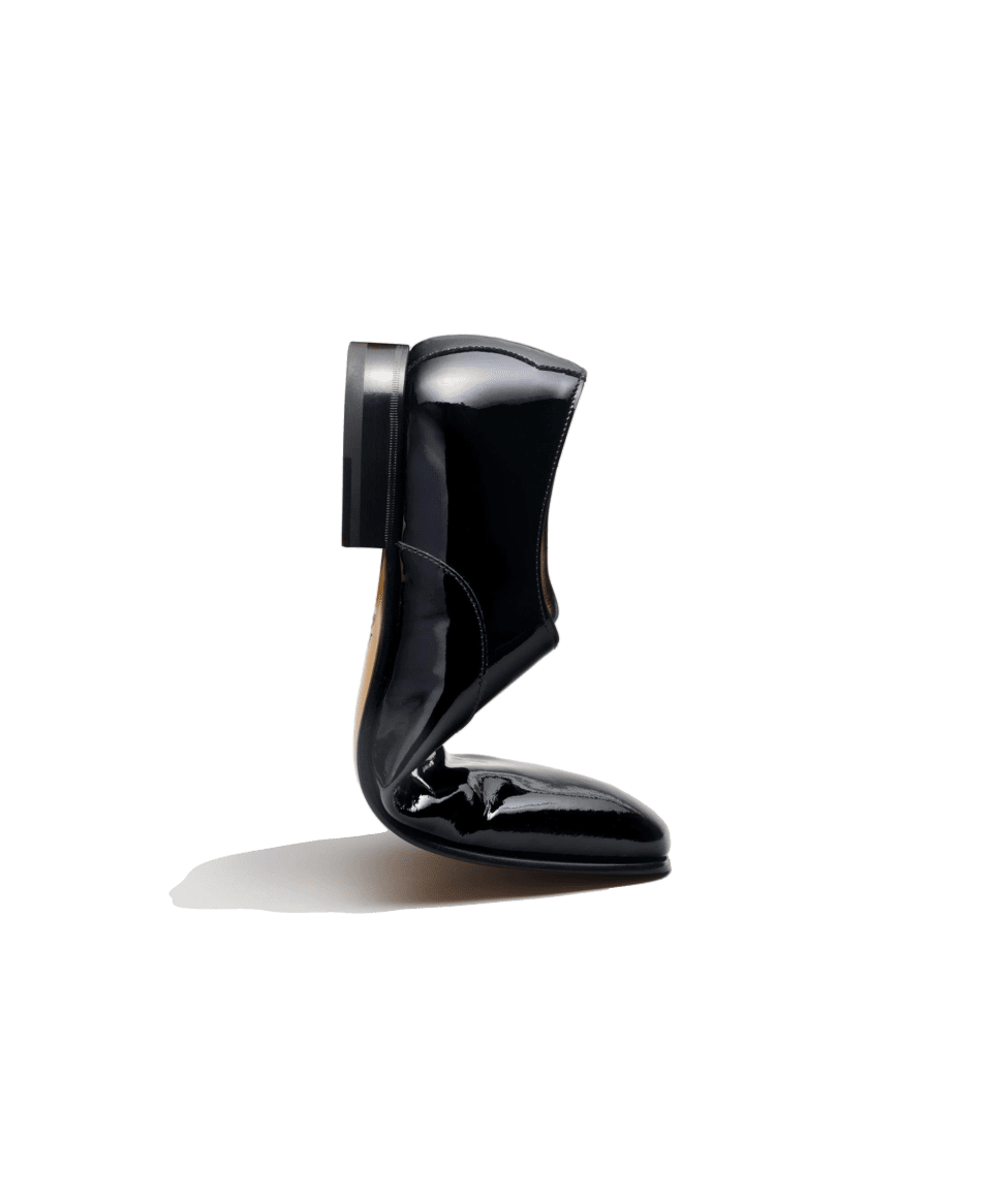 Black patent leather oxford formal shoe, flexed to show sole and toe, on black background