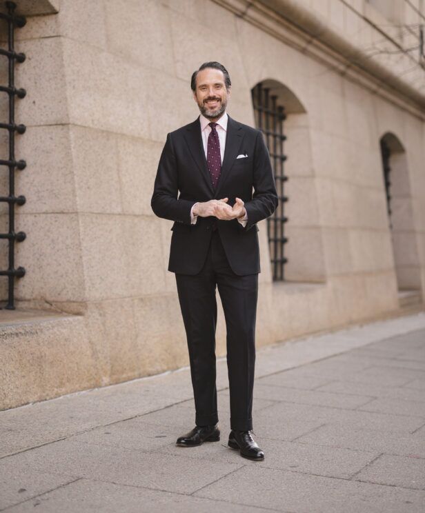 Black flannel suit with pink shirt, burgundy dotted tie and black oxfords, worn on a city street