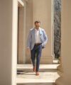 Light blue linen sport coat with white shirt, navy trousers and tan brogues, worn by a model outdoors