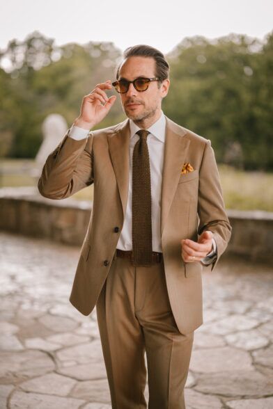 Tan solaro suit with white shirt, brown silk knit tie and gold pocket square, worn by a model outdoors