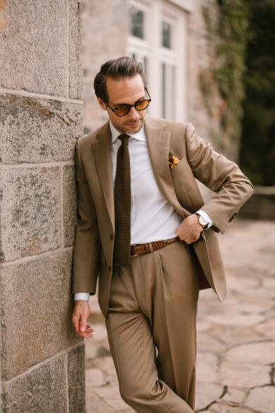 Tan solaro suit with white shirt, brown knit tie and gold dotted pocket square, worn by a model outdoors