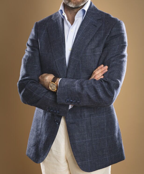 Navy glen check sport coat in textured linen blend with light blue shirt and cream trousers, worn by a model
