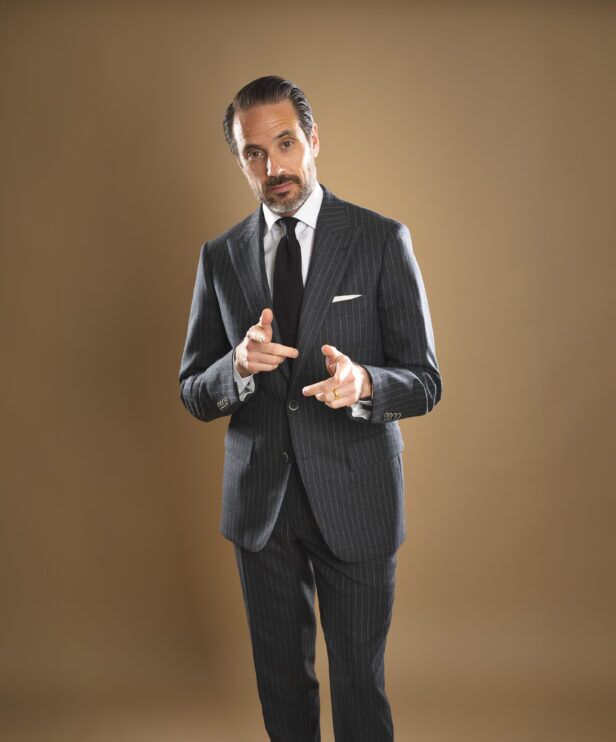 Charcoal chalk stripe flannel suit with white shirt, black knit tie and white pocket square, worn by a model